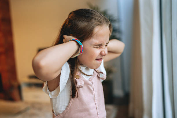 自閉症の子供の女の子は彼女の手の音で彼女の耳を覆っています - 音 ストックフォトと画像